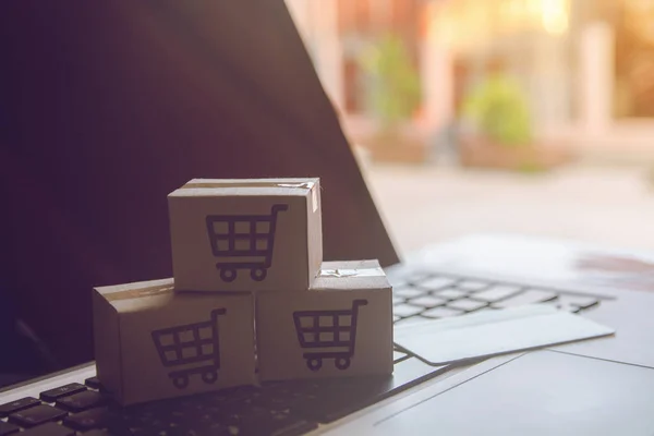Online kavramı alışveriş - online web üzerinde hizmet alışveriş. ödeme kredi kartı ve teklifler eve teslim. bir dizüstü keyboar logosuna parsel veya kağıt karton bir alışveriş sepeti