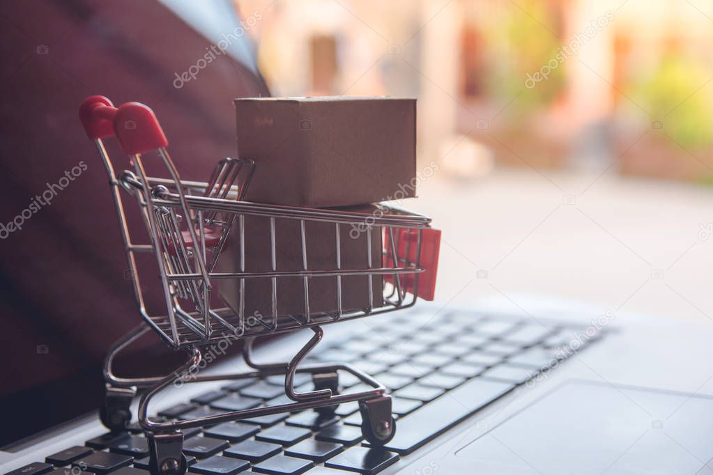 Shopping online concept - Shopping service on The online web. with payment by credit card and offers home delivery. parcel or Paper cartons with a shopping cart on a laptop keyboar