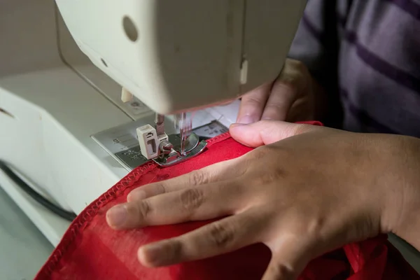 Woman seamstress working making clothes on a sewing machine.