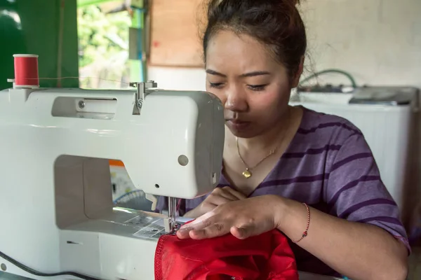 Woman seamstress working making clothes on a sewing machine.