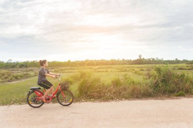 Bisiklet süren bir kadın köy yolunda rahatlar..
