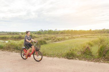 Bisiklet süren bir kadın köy yolunda rahatlar..