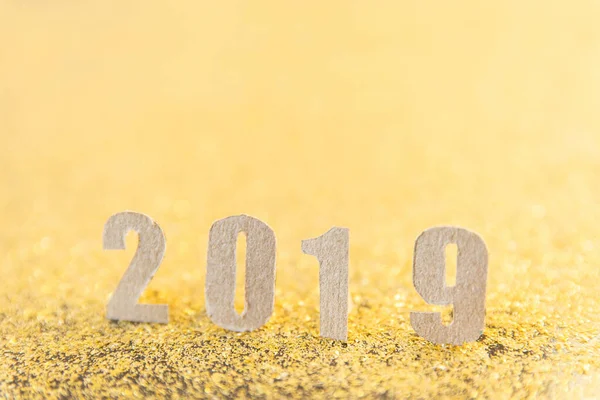 2019 new year text with brown paper on gold glitter background.