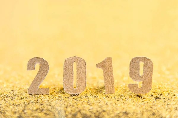 2019 new year text with brown paper on gold glitter background.