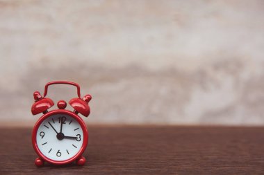 Masanın üzerindeki kırmızı alarmlı saat. Ahşap arka plan, kopyasıyla. 