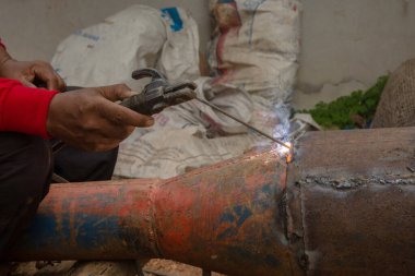 Kaynakçı inşaat alanındaki metal boruları kaynaklıyor.