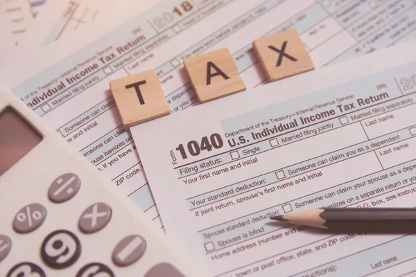 Tax with wooden alphabet blocks, calculator, pencil on 1040 tax — Stock Photo, Image