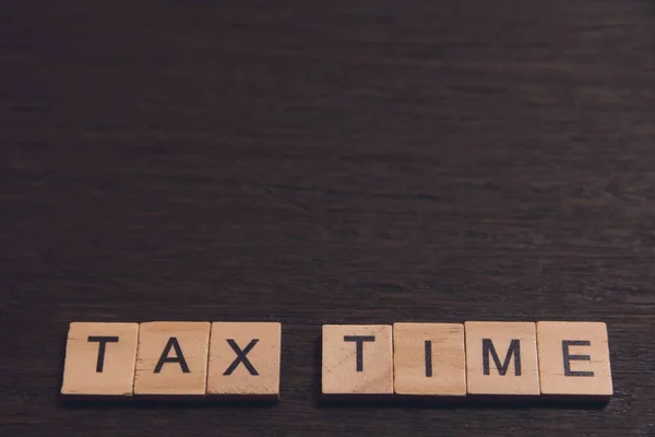Φορολογική ώρα με ξύλινα μπλοκ αλφάβητο σε σκούρα σανίδα ξύλινη backgr — Φωτογραφία Αρχείου