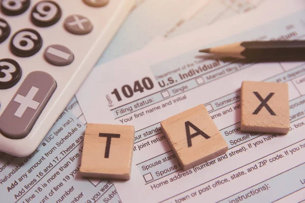 Impuesto con bloques de alfabeto de madera, calculadora, lápiz en el impuesto 1040 — Foto de Stock