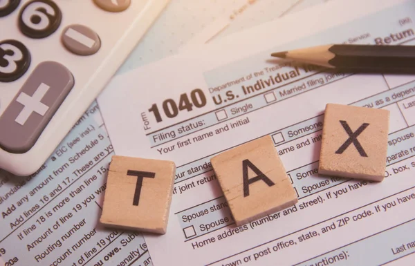 Impuesto con bloques de alfabeto de madera, calculadora, lápiz en el impuesto 1040 — Foto de Stock