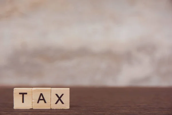Steuer mit Buchstabenwürfel aus Holz auf Tisch dunkle Holzplanke — Stockfoto