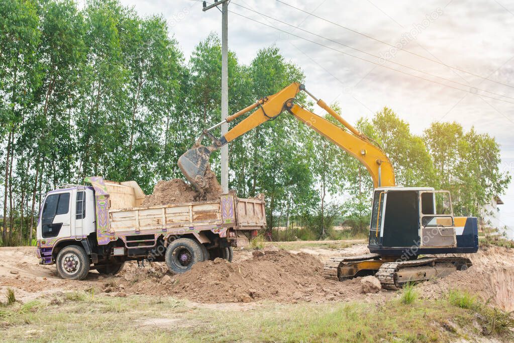 Yellow excavator machine loading soil into a dump truck at const