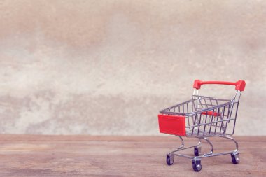 Alışveriş konsepti: Kahverengi ahşap masada boş kırmızı alışveriş arabası. 