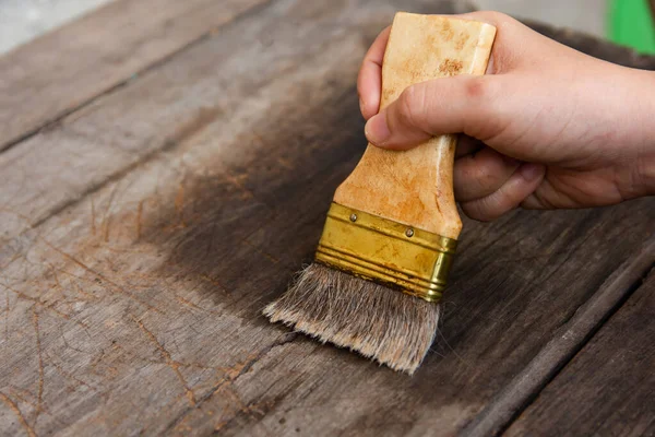 Main tenant un pinceau Peinture des planches de bois surface avec — Photo