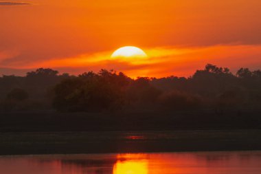 Gün batımı göldeki bulutların arkasında.
