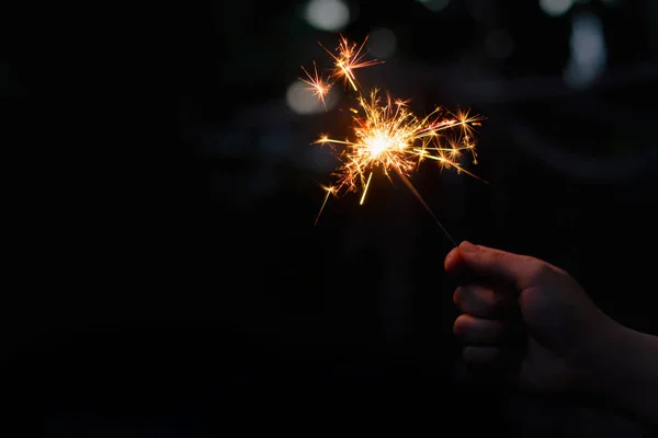 Kvinnlig hand håller en brinnande tomtebloss — Stockfoto