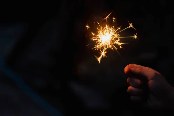 Kvinnlig hand håller en brinnande tomtebloss — Stockfoto