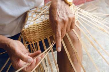 Kıdemli adam elleriyle bambu örüyor..