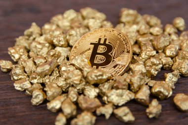Koyu ahşap arka planda altın külçeler üzerinde altın bitcoin