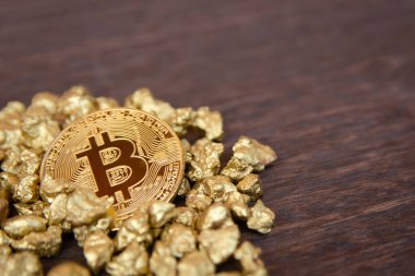 Koyu ahşap arka planda altın külçeler üzerinde altın bitcoin