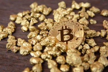 Koyu ahşap arka planda altın külçeler üzerinde altın bitcoin