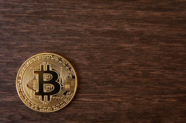 Koyu ahşap zemin üzerinde fotokopi alanı olan Bitcoin altın sikkesi