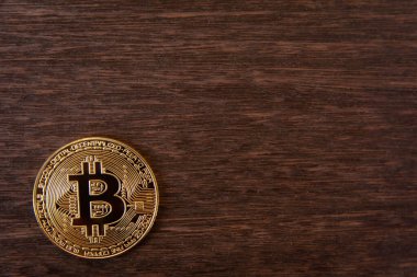 Koyu ahşap zemin üzerinde fotokopi alanı olan Bitcoin altın sikkesi