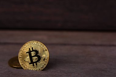Koyu ahşap zemin üzerinde fotokopi alanı olan Bitcoin altın sikkesi