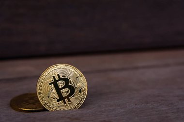Koyu ahşap zemin üzerinde fotokopi alanı olan Bitcoin altın sikkesi