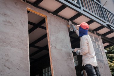 İnşaat işçileri inşaat duvarlarını beton kaplamalarıyla sıva yapıyorlar.