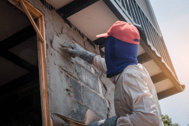 İnşaat işçileri inşaat duvarlarını beton kaplamalarıyla sıva yapıyorlar.