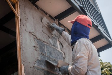 İnşaat işçileri inşaat duvarlarını beton kaplamalarıyla sıva yapıyorlar.