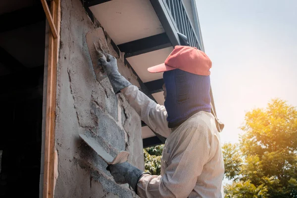 Trabalhadores da construção civil que rebocam a parede do edifício usando o emplastro do cimento — Fotografia de Stock