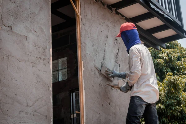 Trabalhadores da construção civil que rebocam a parede do edifício usando o emplastro do cimento — Fotografia de Stock