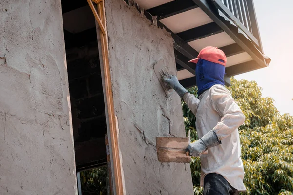 Trabalhadores da construção civil que rebocam a parede do edifício usando o emplastro do cimento — Fotografia de Stock