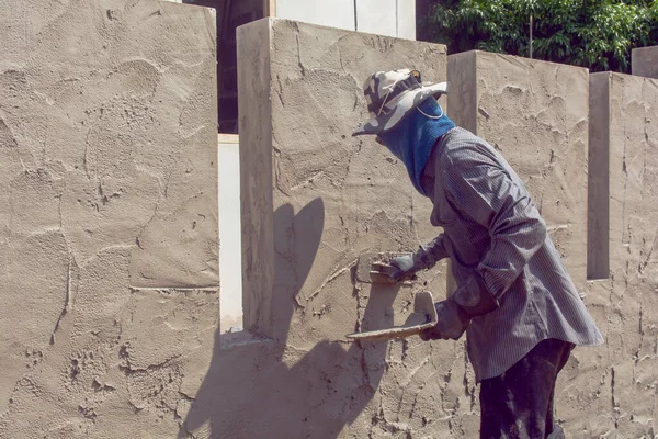 Construction workers plastering building wall using cement plast