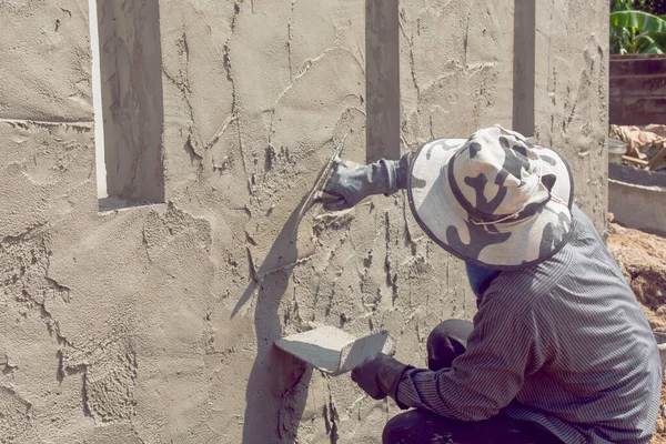 Construction workers plastering building wall using cement plast