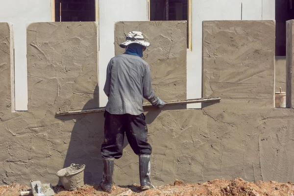 Construction workers plastering building wall using cement plast