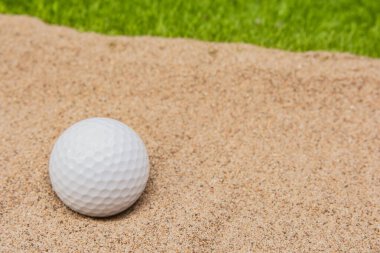 Golf sahasındaki kum sığınağında beyaz golf topu.