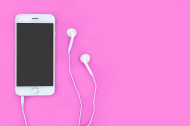 Kulaklıklı akıllı telefon pembe arka planda fotokopi alanı ve