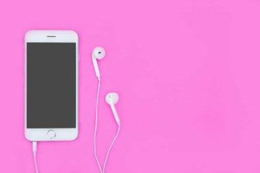 Kulaklıklı akıllı telefon pembe arka planda fotokopi alanı ve
