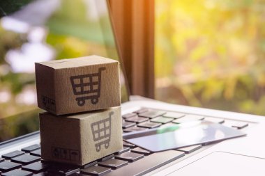 İnternetten alışveriş, kağıt kutular ya da klavyede alışveriş arabası logosu ve kredi kartı olan bir paket. İnternet üzerinden alışveriş hizmeti sunuyor..
