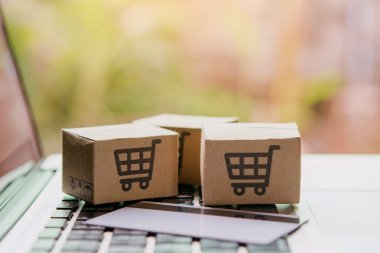 İnternetten alışveriş, kağıt kutular ya da klavyede alışveriş arabası logosu ve kredi kartı olan bir paket. İnternet üzerinden alışveriş hizmeti sunuyor..