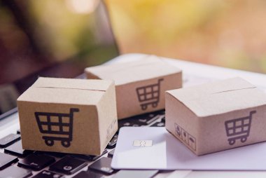 İnternetten alışveriş, kağıt kutular ya da klavyede alışveriş arabası logosu ve kredi kartı olan bir paket. İnternet üzerinden alışveriş hizmeti sunuyor..