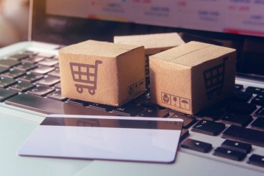 İnternetten alışveriş, kağıt kutular ya da klavyede alışveriş arabası logosu ve kredi kartı olan bir paket. İnternet üzerinden alışveriş hizmeti sunuyor.