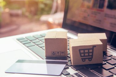 İnternetten alışveriş, kağıt kutular ya da klavyede alışveriş arabası logosu ve kredi kartı olan bir paket. İnternet üzerinden alışveriş hizmeti sunuyor.