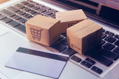 İnternetten alışveriş, kağıt kutular ya da klavyede alışveriş arabası logosu ve kredi kartı olan bir paket. İnternet üzerinden alışveriş hizmeti sunuyor.