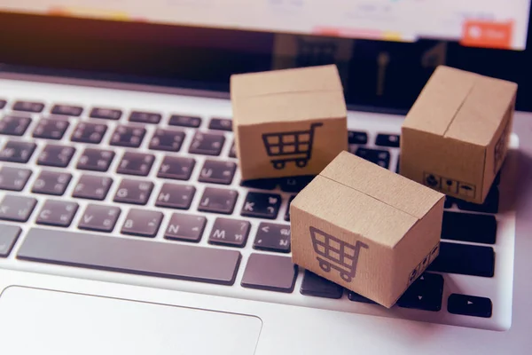 Online shopping - Paper cartons or parcel with a shopping cart logo on a laptop keyboard. Shopping service on The online web and offers home delivery