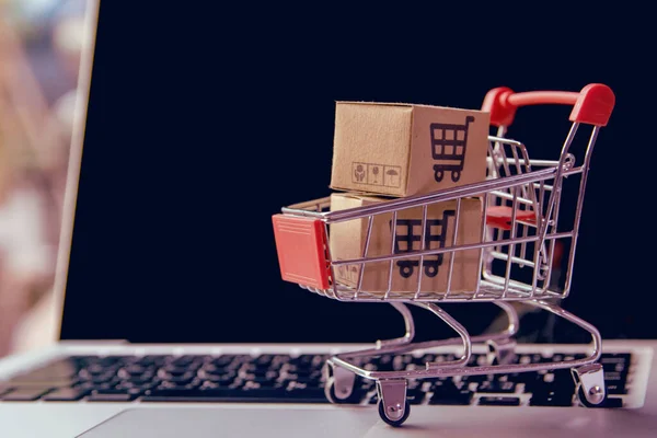 网上购物概念 在笔记本电脑键盘上的推车上有购物车标识的包裹或纸箱 网上购物服务 提供上门送货服务 — 图库照片