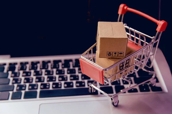 网上购物概念 在笔记本电脑键盘上的推车上有购物车标识的包裹或纸箱 网上购物服务 提供上门送货服务 — 图库照片